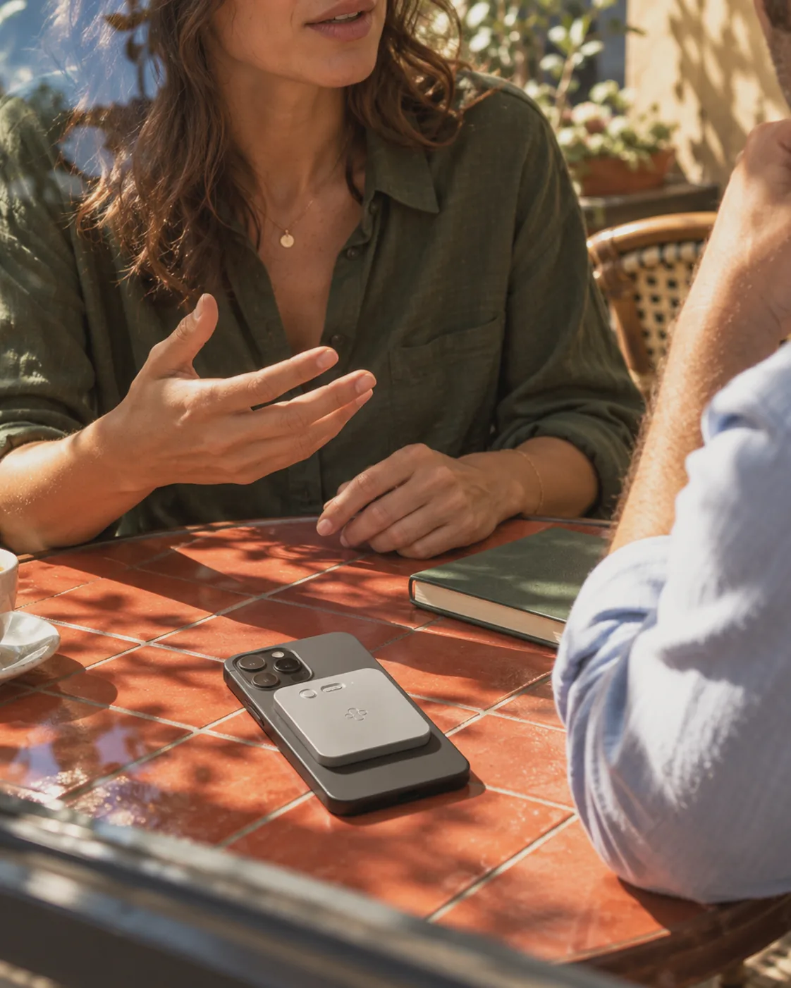 Two people talking at a café table, with Jase Slate on a phone between them